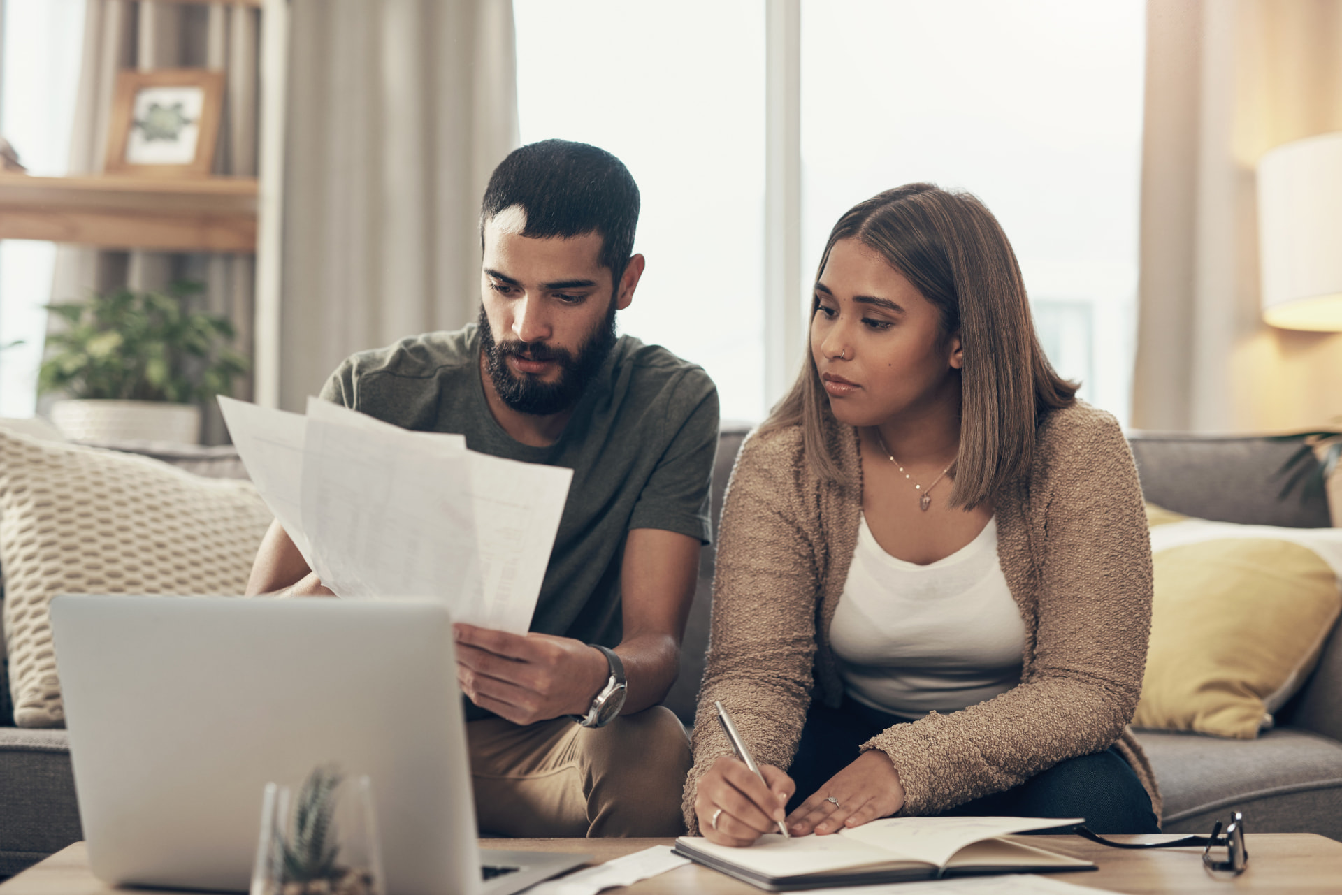 Pareja latina revisando papeles y presupuesto en su sala